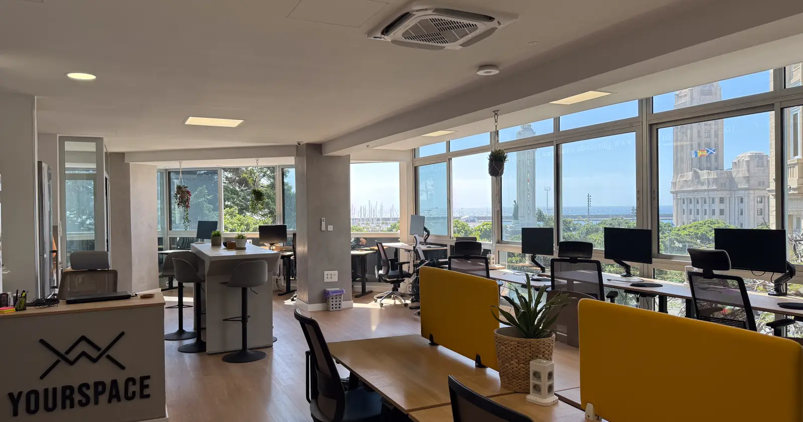 Recepción y zona de trabajo · Vista completa desde la entrada: recepción, puestos abiertos y taquillas en un mismo espacio.