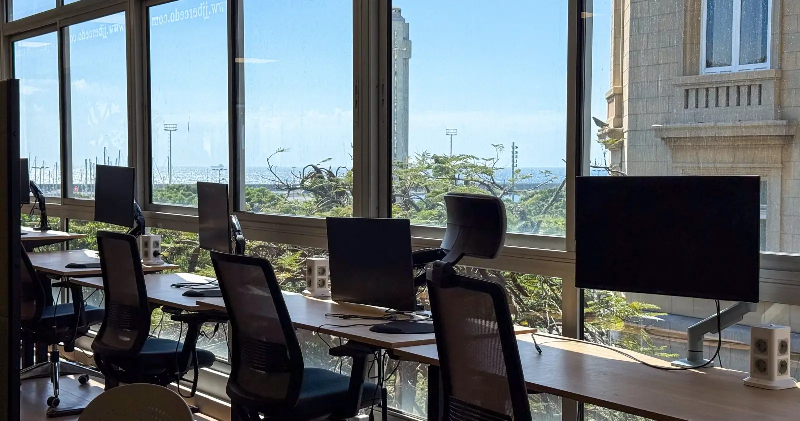 Puestos junto a la ventana · Mesas regulables, monitores y sillas ergonómicas preparadas para trabajar con comodidad.
