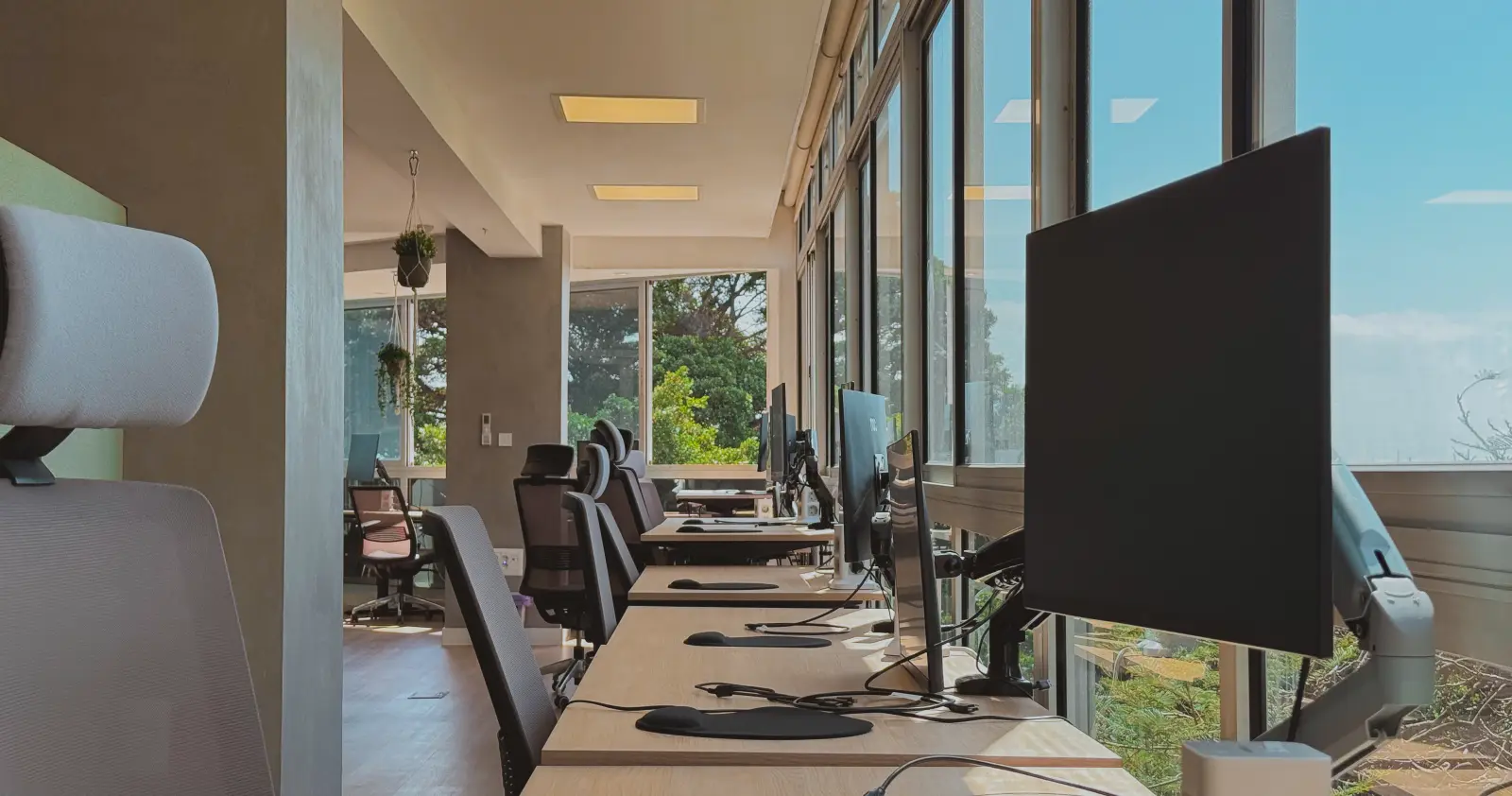 Zona de puestos · Mesas con monitor y enchufes integrados, listas para empezar a trabajar.